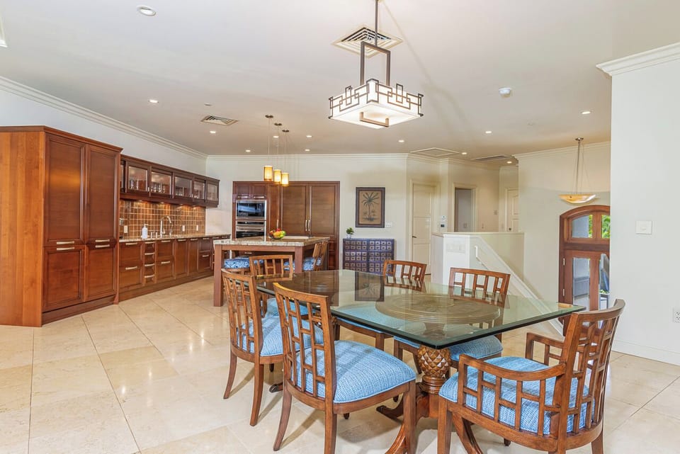 Step into your open-concept kitchen and dining space, where rich wood cabinetry meets elegant details. Gather around the glass-top table under statement lighting—perfect for your morning coffee or evening meal together.