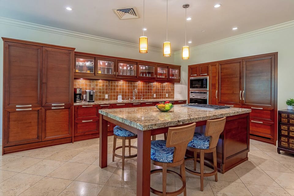 Your dream culinary space awaits—warm wood cabinetry, granite countertops, and a breakfast bar invite you to create delicious memories together in this inviting, fully-equipped kitchen.