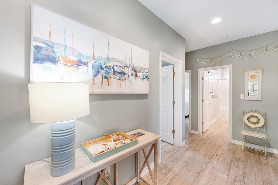 Coastal-themed entryway welcomes you with nautical artwork, starfish garland, and charming seashell touches throughout this beach-inspired hallway.