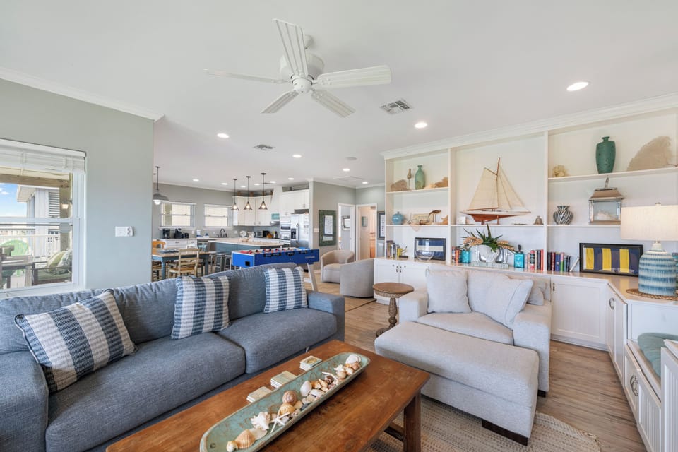 Relax in this bright coastal living space where nautical charm meets modern comfort, complete with built-in entertainment center and open kitchen.