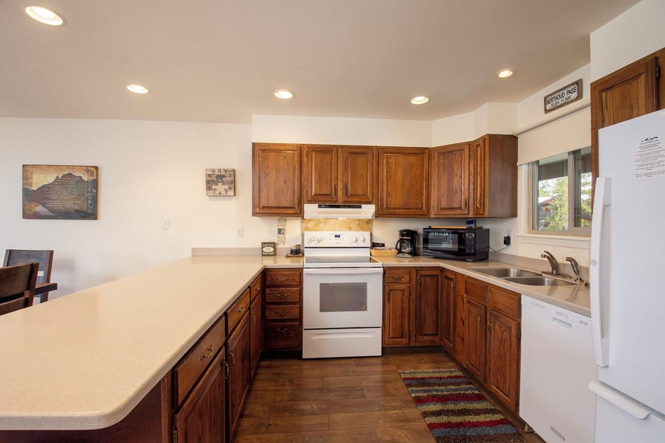 Your spacious U-shaped kitchen offers rich wood cabinetry, generous counter space, and all essential appliances for preparing memorable meals during your stay.