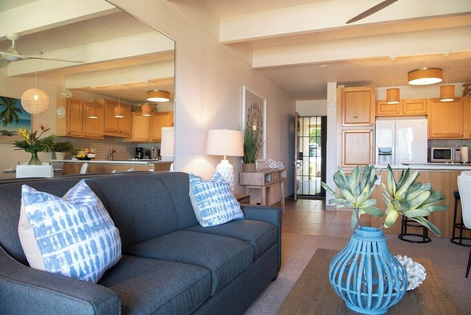 A living room with coastal accents and comfy seating, flowing seamlessly into the kitchen.