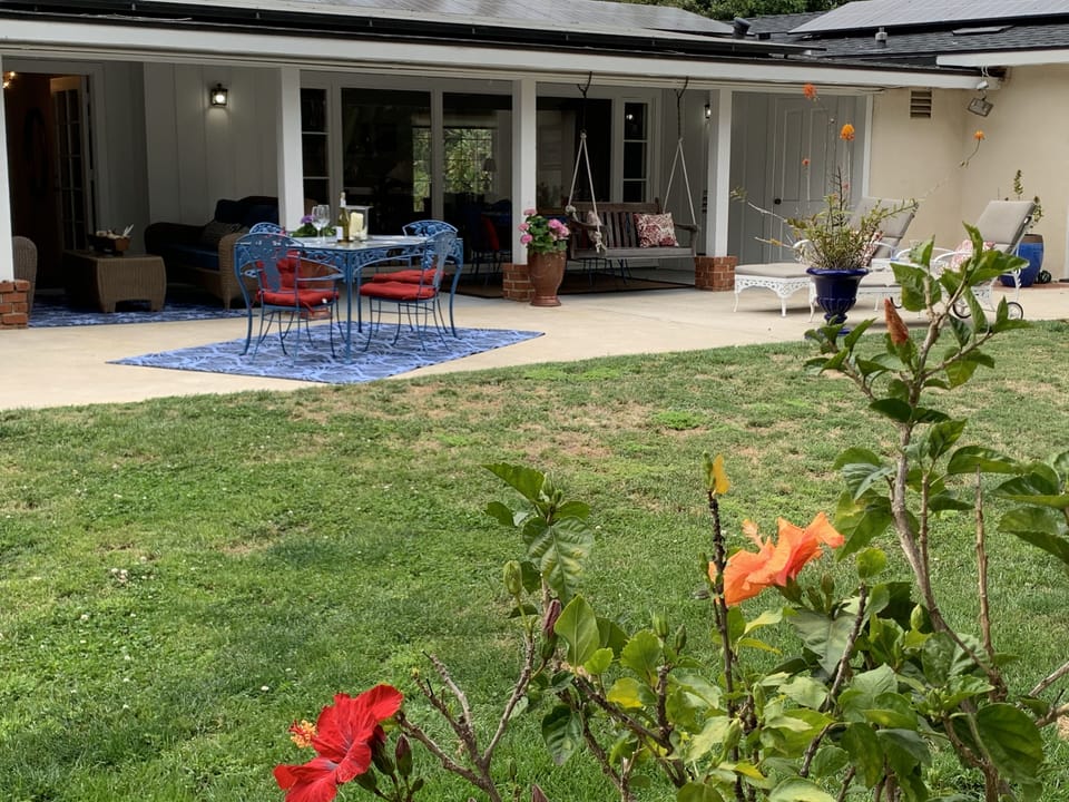 Huge fenced back yard with flowers, ferns and big trees. Lot of out sitting area