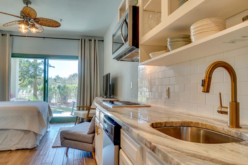 Relax in your stylish open-plan space with a fully equipped kitchen, comfortable seating, and peaceful garden views beyond the patio doors.