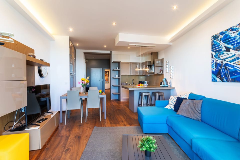 Bright, modern living room with a fully equipped open kitchen. Warm ambiance with vibrant colors and functional design for relaxation.