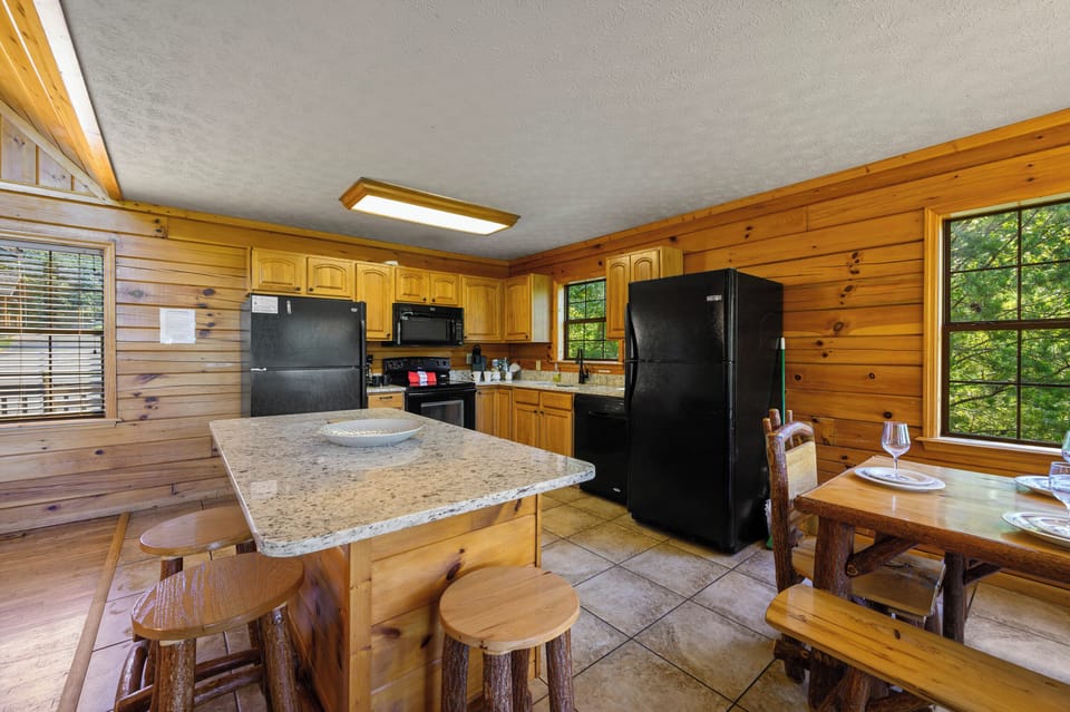 Kitchen with island, electric range, oven, microwave and two refrigerators.