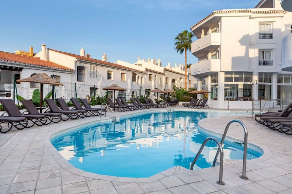 Tranquil resort pool area with ample sun loungers, inviting guests to relax and soak up the sunshine.