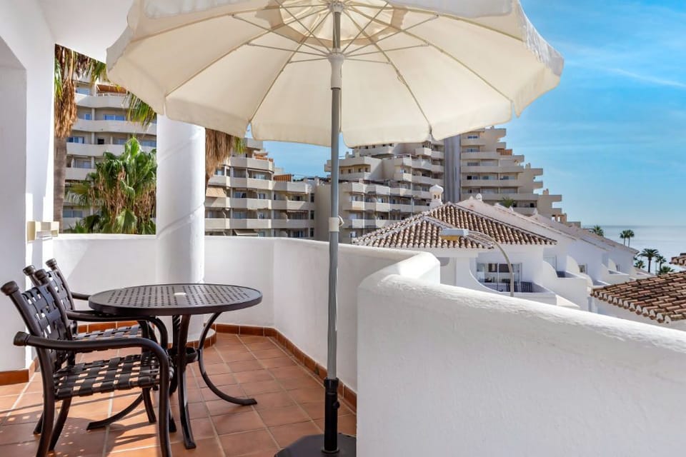 Private balcony retreat with seating and umbrella, perfect for enjoying the cityscape and a breath of fresh air.