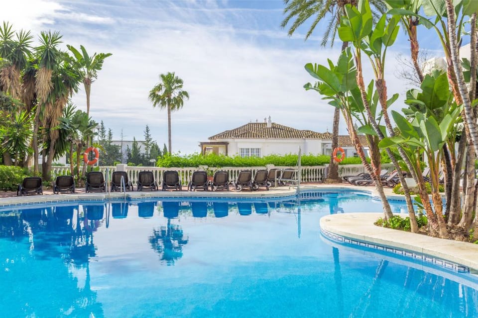 Dive into the crystal blue waters of a pool that invites leisurely days under the open sky amidst tropical palms.