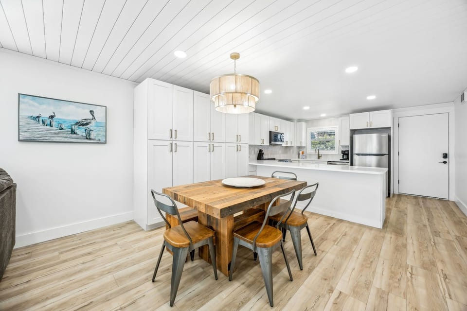 Your bright, modern kitchen-dining space combines style and function with gleaming white cabinetry, warm wood floors, and a welcoming table for memorable meals together.