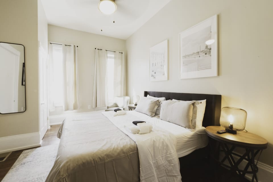 The Beige Room is a private bedroom with queen bed, mirror, and smart TV.