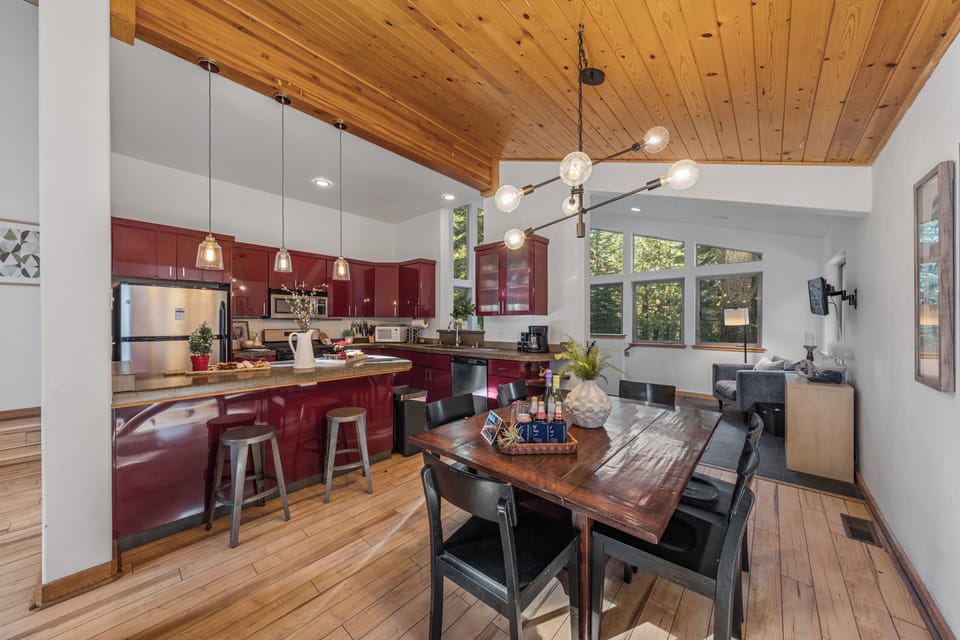 Open-concept kitchen and dining area with vaulted wood ceilings and bar seating.