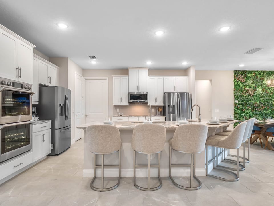 - Spacious kitchen with sleek white cabinetry and stainless appliances  
- Large island bar with stool seating ideal for family gatherings  
- Fully equipped vacation rental kitchen ready for group meals