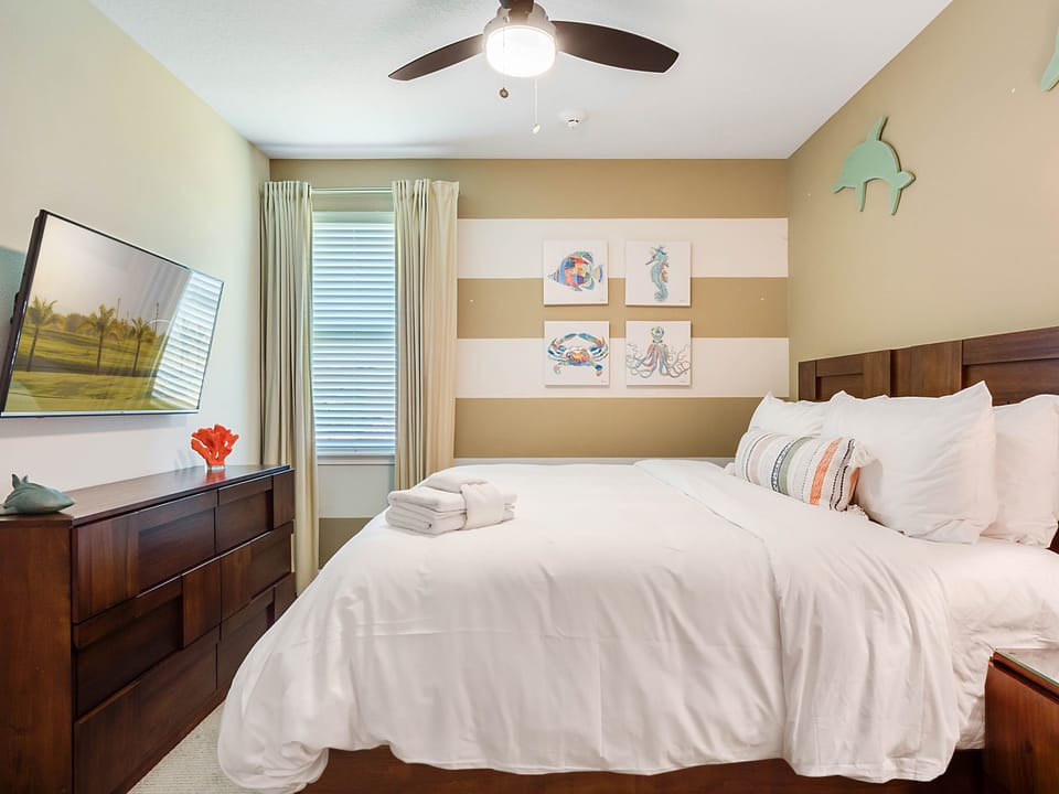 - Bedroom with queen bed and ocean inspired wall art for style  
- Earth tone design paired with striped accent wall feels coastal  
- TV and decor details make it a relaxing seaside-inspired stay