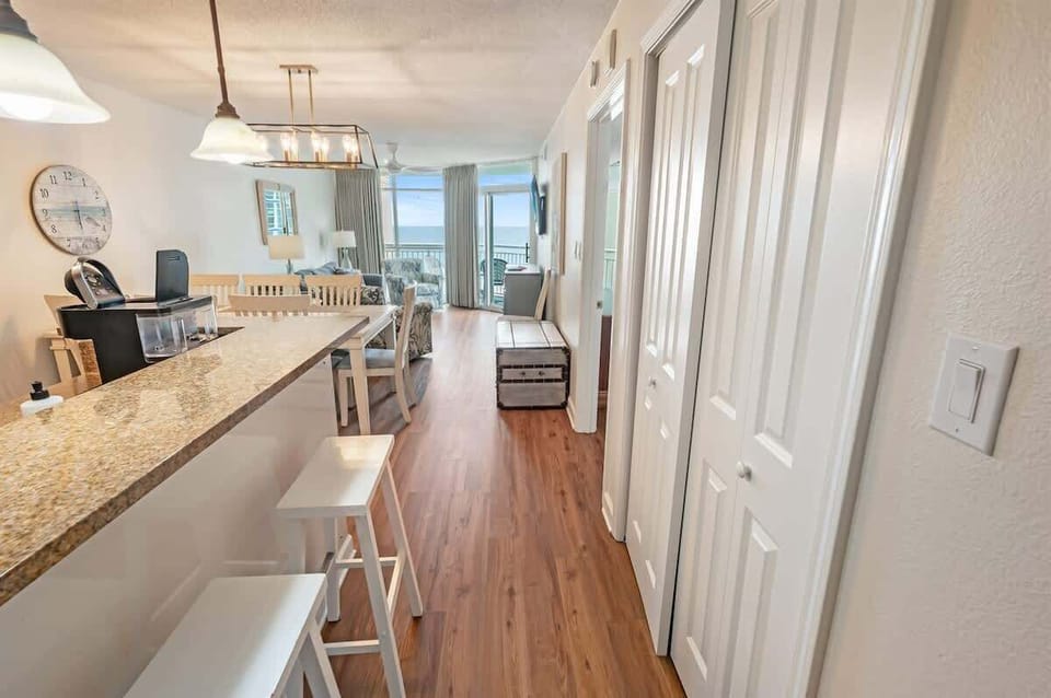 - Granite countertop breakfast bar with modern lighting   - Bar stools create casual seating by the kitchen area   - Open layout flows into dining and living with ocean view