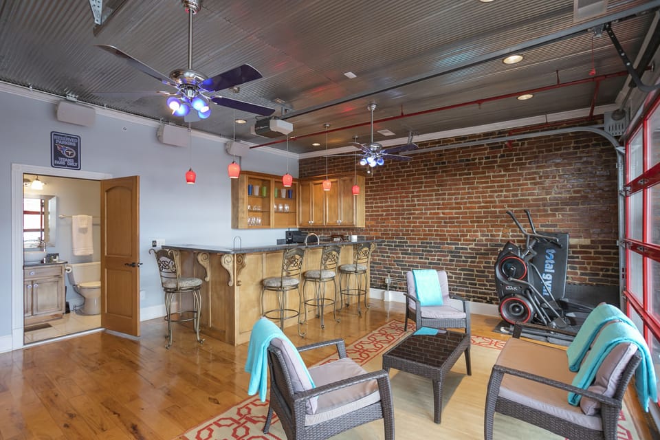 - Nashville loft bar lounge with brick walls and cozy seating   - Built-in bar and ceiling fans create an inviting hangout   - Great space for relaxing before heading downtown
