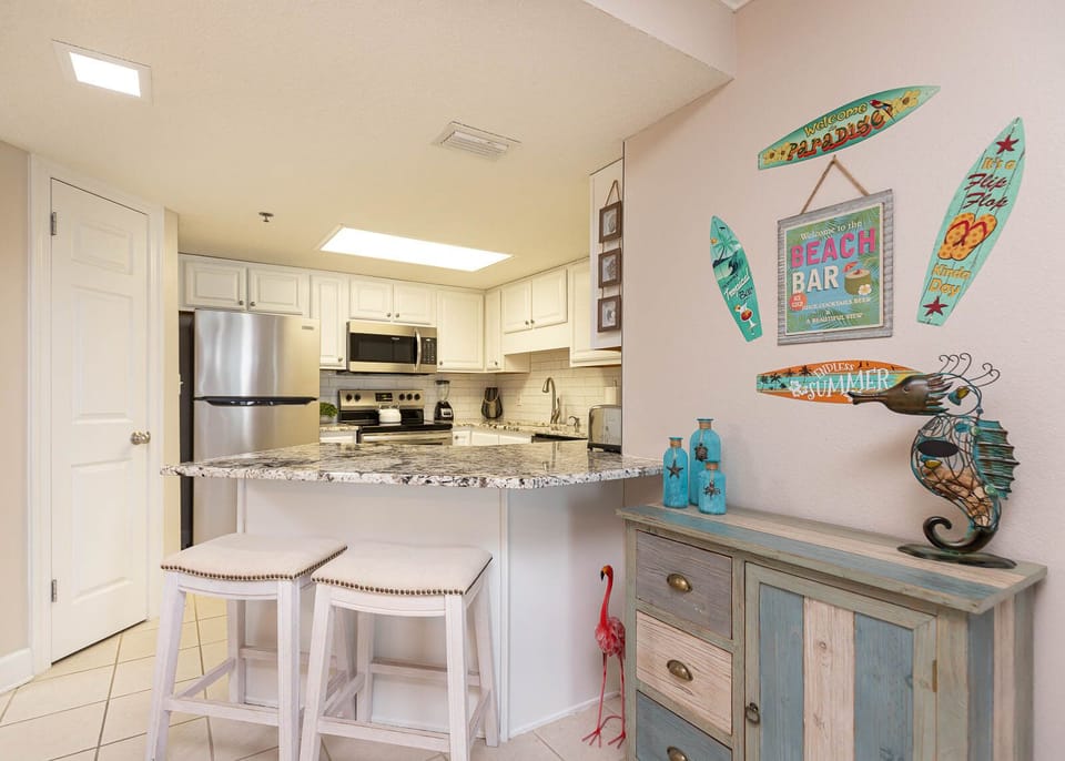 Kitchen area features a granite breakfast bar with seating, stylish decor, and stainless appliances for a welcoming vibe