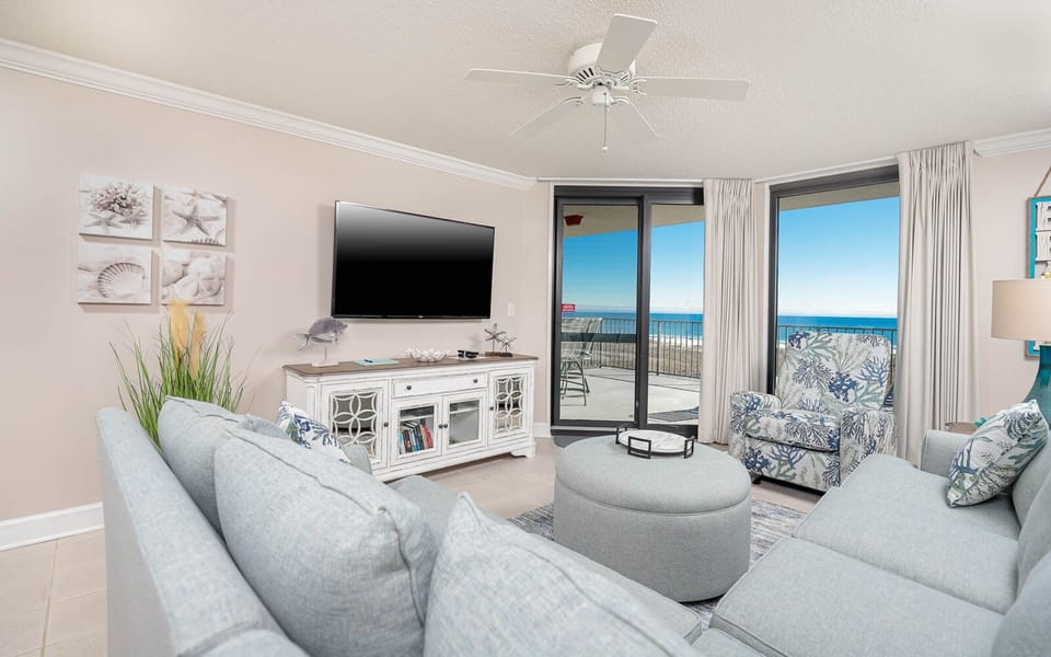 Cozy living area features a large TV, stylish seating with queen sofa-sleeper, and balcony with a beautiful view of the gulf