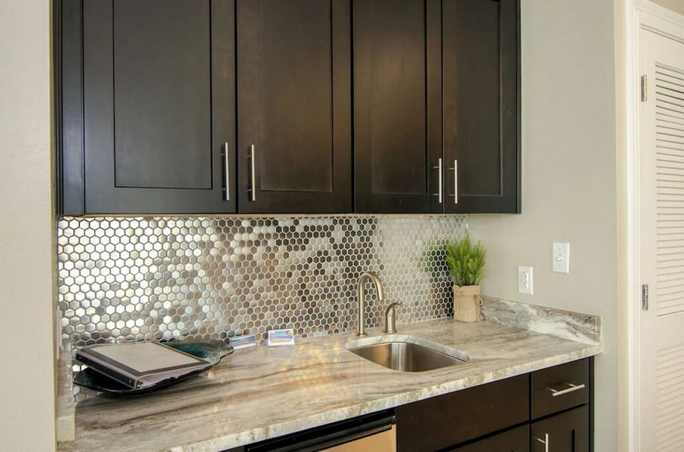 Granite Countertop, Stainless Sink, Tile Backsplash, Cabinets, Guestbook, Plant.