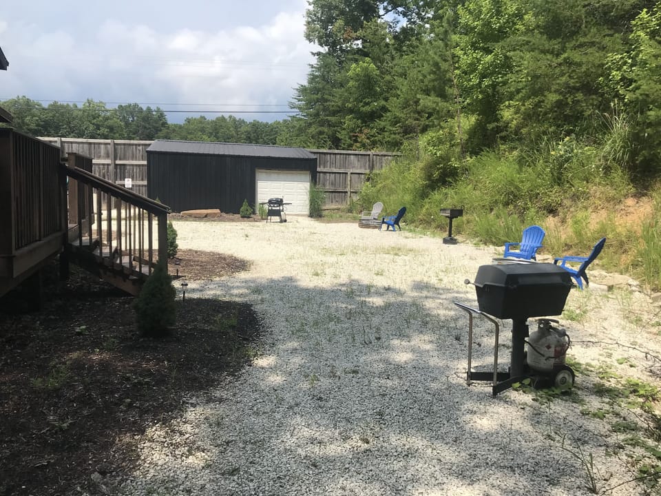 View of grills and fire pits with building that has wood provided in dry storage