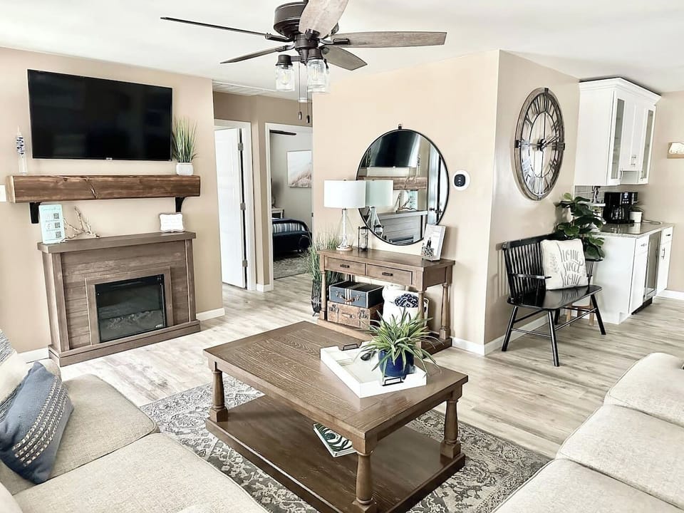 Gather around the warm electric fireplace in our inviting living room. This space features a large flat-screen TV, stylish coffee bar area, and comfortable seating—perfect for cozy evenings in after a long day at the beach.