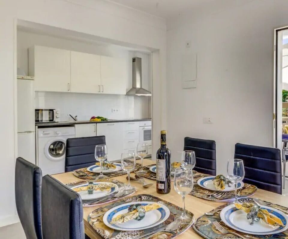 Dining for six beside the open kitchen with direct access to the terrace and outdoor table under a parasol.