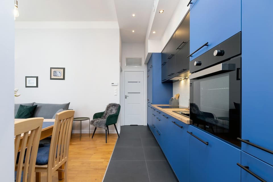 A stylish kitchen with blue cabinets, wooden countertops, and a unique, contemporary design.
