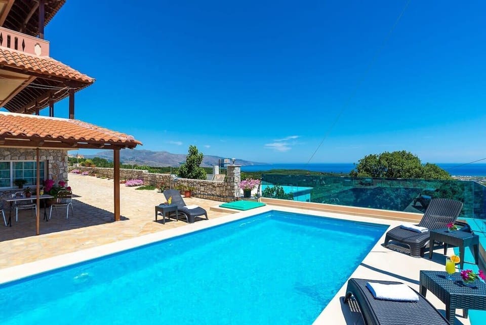 Poolside Relaxation with Scenic Horizon – Spacious shared pool between two properties, framed by sun loungers and breathtaking horizon views.