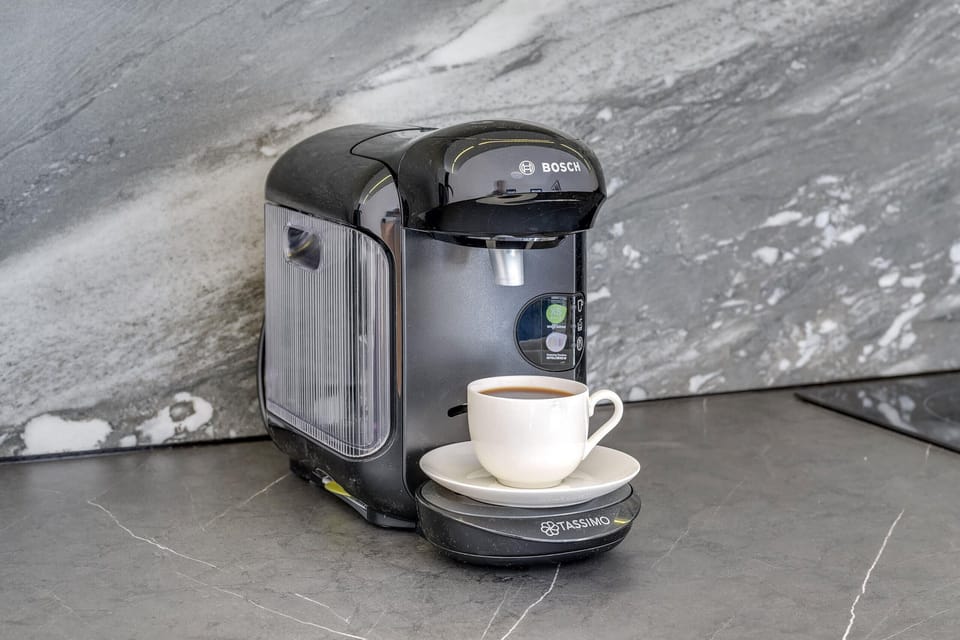 A modern coffee maker placed on a gray marble countertop. The setup is convenient and stylish for coffee enthusiasts.