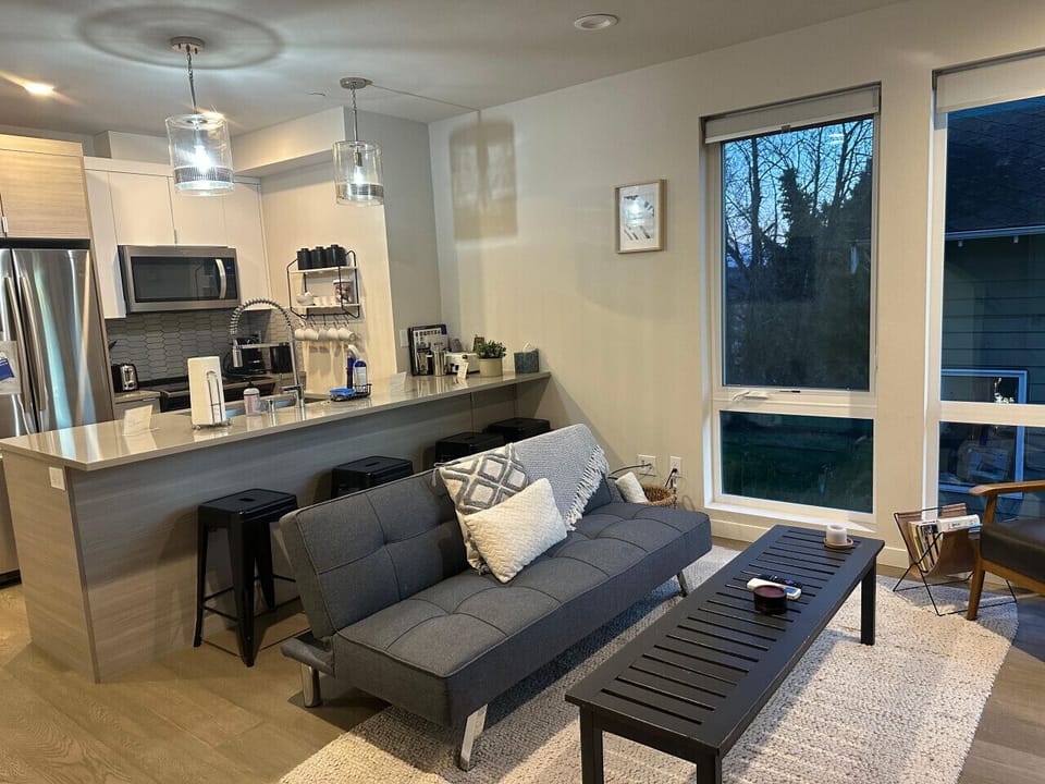 Bright open-concept space with a modern kitchen, breakfast bar with seating, and cozy living area filled with natural light.
