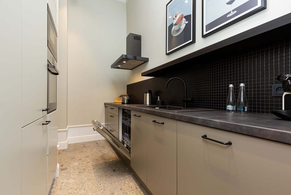 A sleek kitchen with dark countertops, light cabinetry, and stainless steel appliances, designed for functionality.