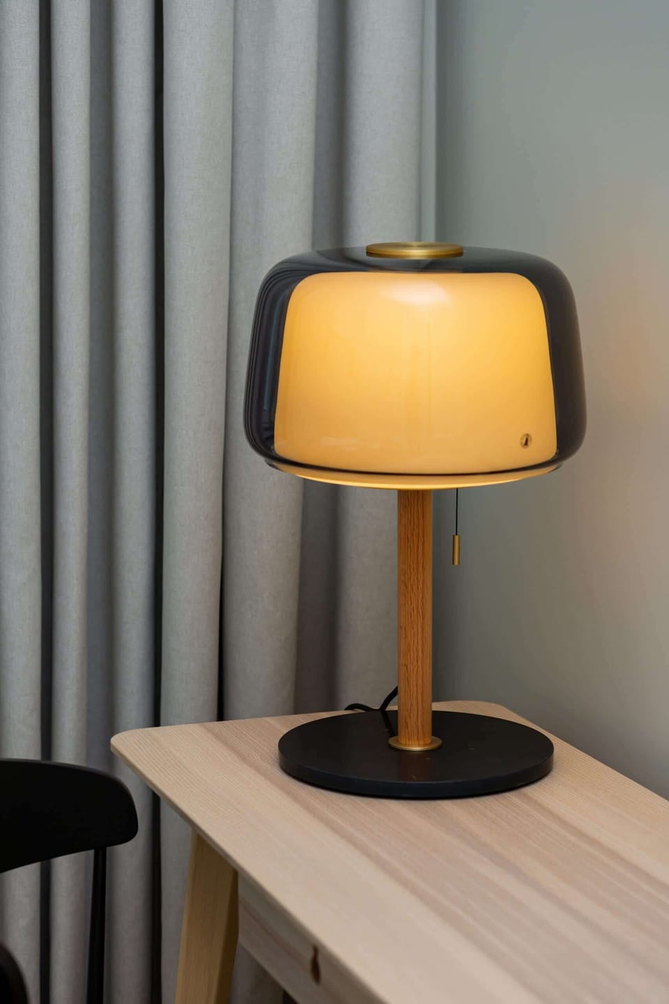 A bedside table with a warm-lit lamp, adding a cozy and inviting feel to the room.