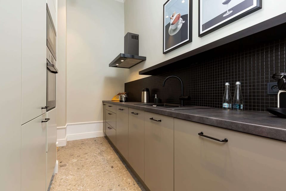 A sleek kitchen with dark countertops, light cabinetry, and stainless steel appliances, designed for functionality.