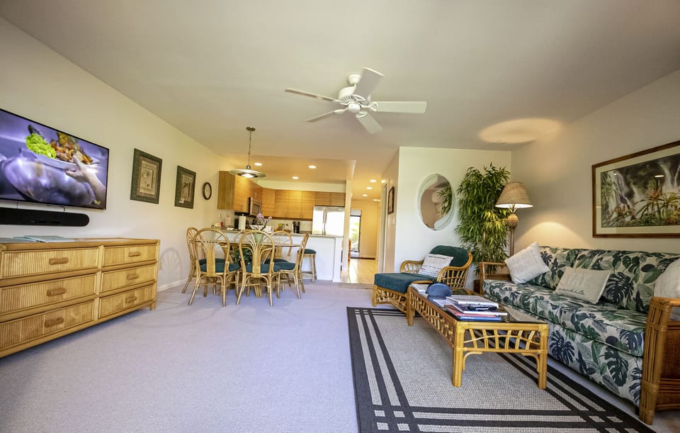 Bright, open living space flows into a dining nook and kitchen, with tropical-print seating, ceiling fan, and flat-screen for your downtime comfort.