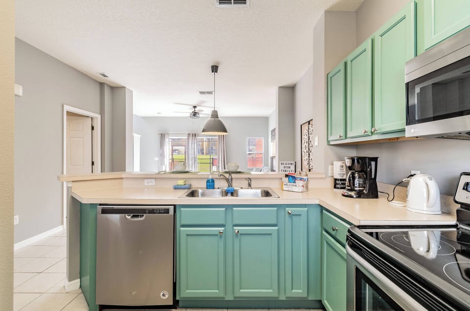 Step into a cheerful kitchen featuring soft mint green cabinetry that beautifully contrasts with the sleek black appliances. Natural light streams in, enhancing the inviting atmosphere as you envision preparing meals with ease.