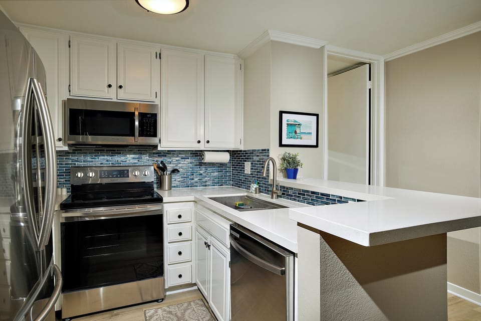 The kitchen has been remodeled with quartz countertops, stainless appliances, and a gorgeous designer backsplash.
