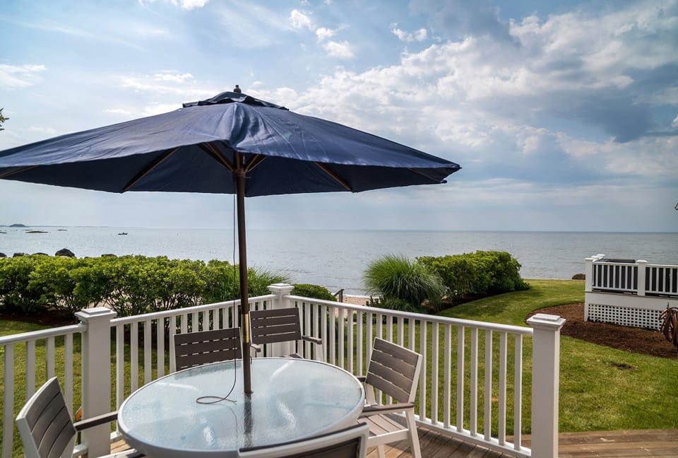Side deck with dining area and grill overlooking ocean
