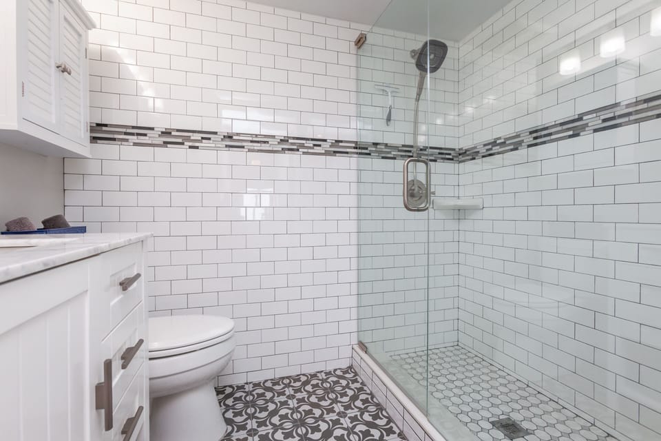 Primary bath. Art deco floor tile in both baths. Large shower head, handheld.