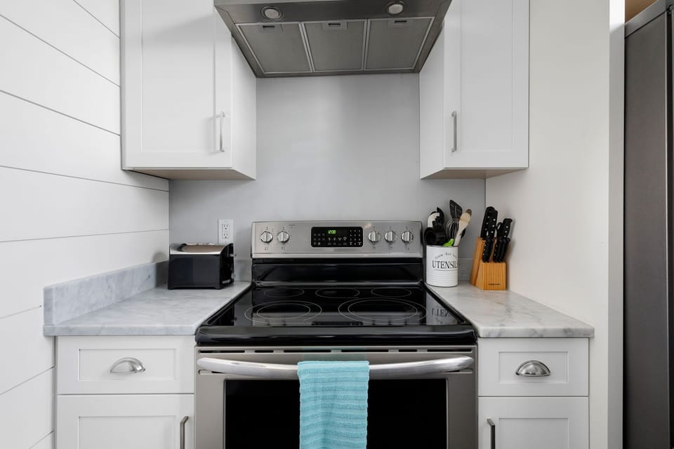 High-end stainless steel appliances including a full-size fridge and electric stove.