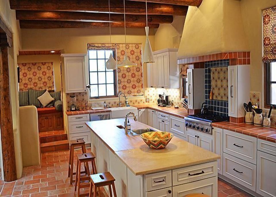 Reverse view of kitchen with alcove in back left featuring large window seat, computer/task desk and swing mounted television (unseen) facing into alcove