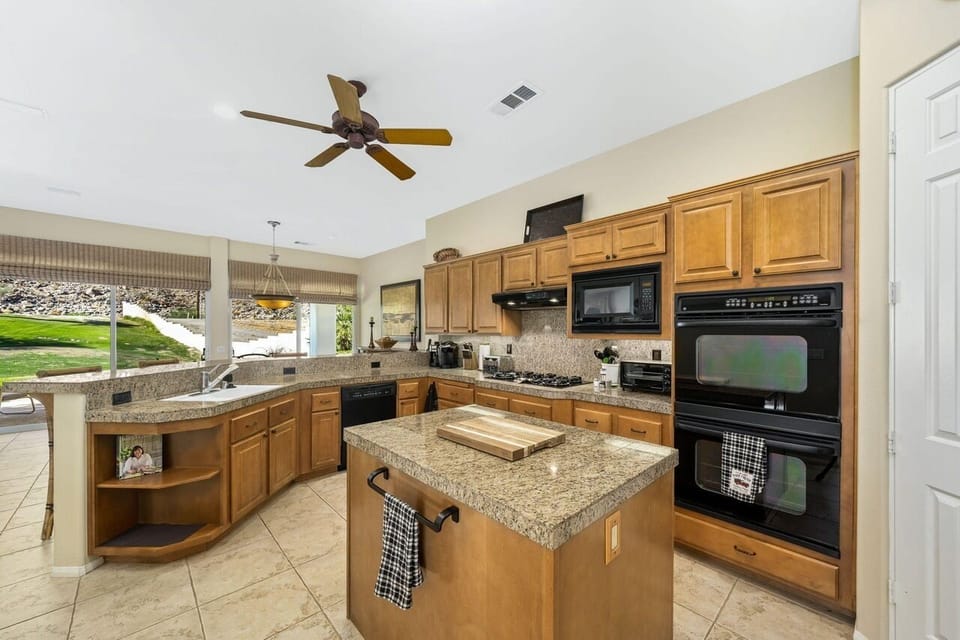 Kitchen features large island, five burner cooktop, dishwasher and double sink. 