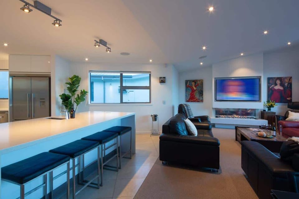 Bright and Stylish Living Room – A perfect blend of comfort and elegance, featuring expansive windows, modern furnishings, and breathtaking views of Lake Wakatipu and The Remarkables.