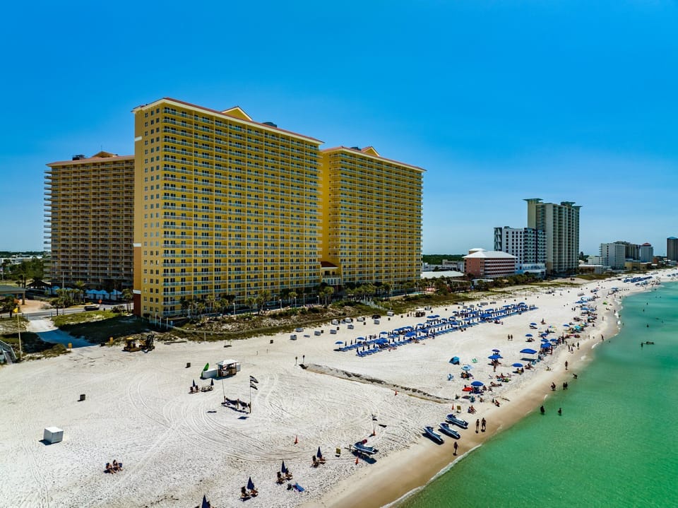 Calypso Resort and Towers from above, sitting directly on the sugar-white sand of Panama City Beach with the emerald Gulf right at the doorstep.