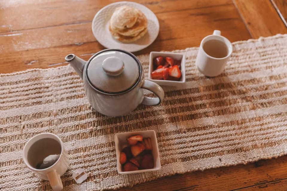 Breakfast setup featuring tea, pancakes, and fresh strawberries