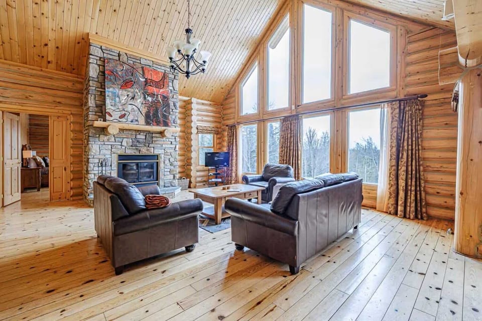 Living room with high vaulted ceilings, large windows, and stone fireplace