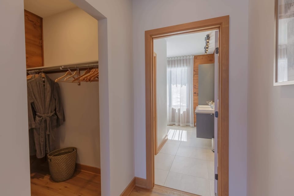 Walk-in closet with robes and storage, leading to a bright and elegant ensuite bathroom