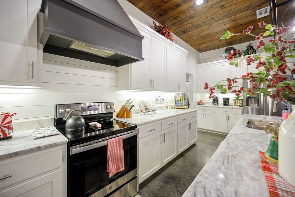Your fully equipped kitchen invites culinary adventures with sleek marble counters, modern appliances, and warm wood ceiling details.