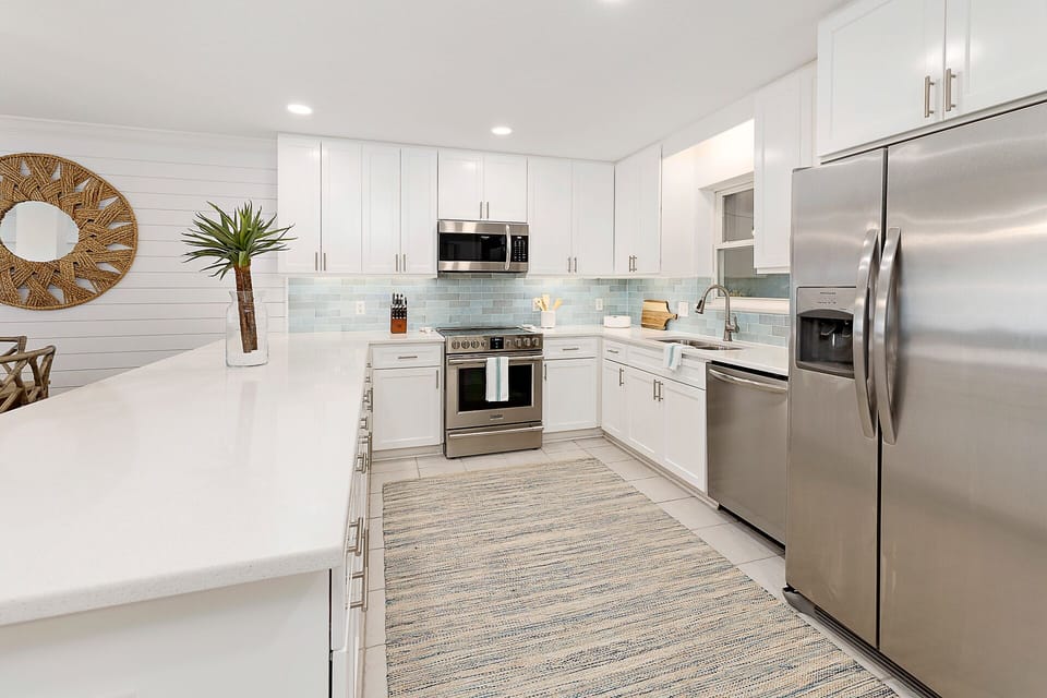 Kitchen features stainless steel appliances and beautiful white countertops.