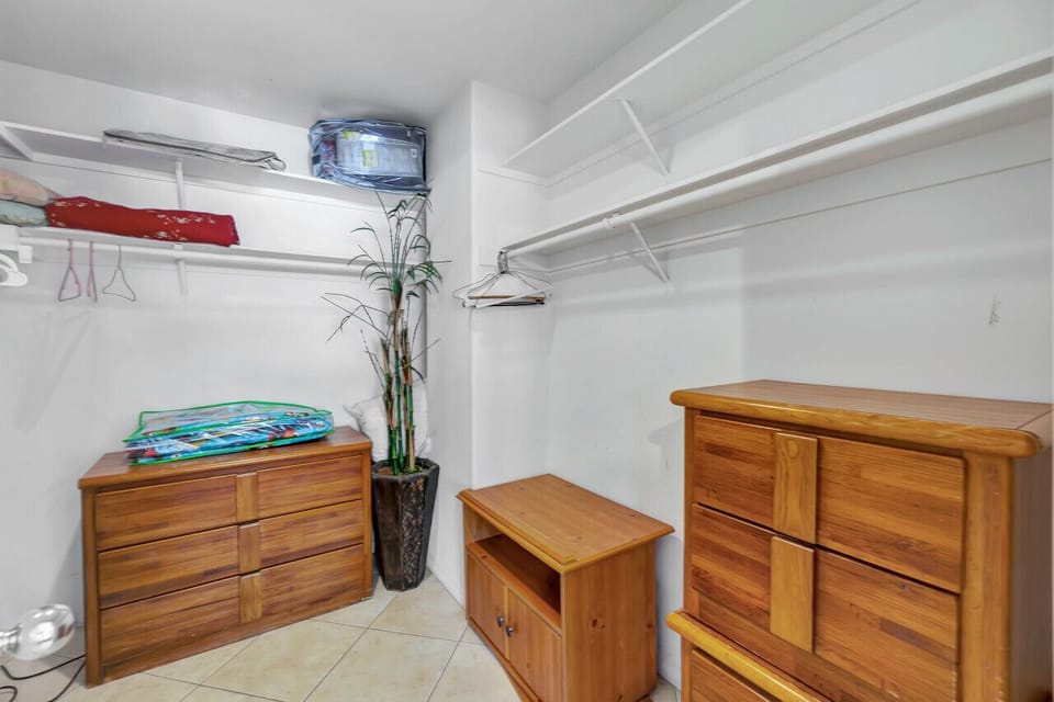 Large walk-in closet w/ built-in shelves & wood dressers for easy storage