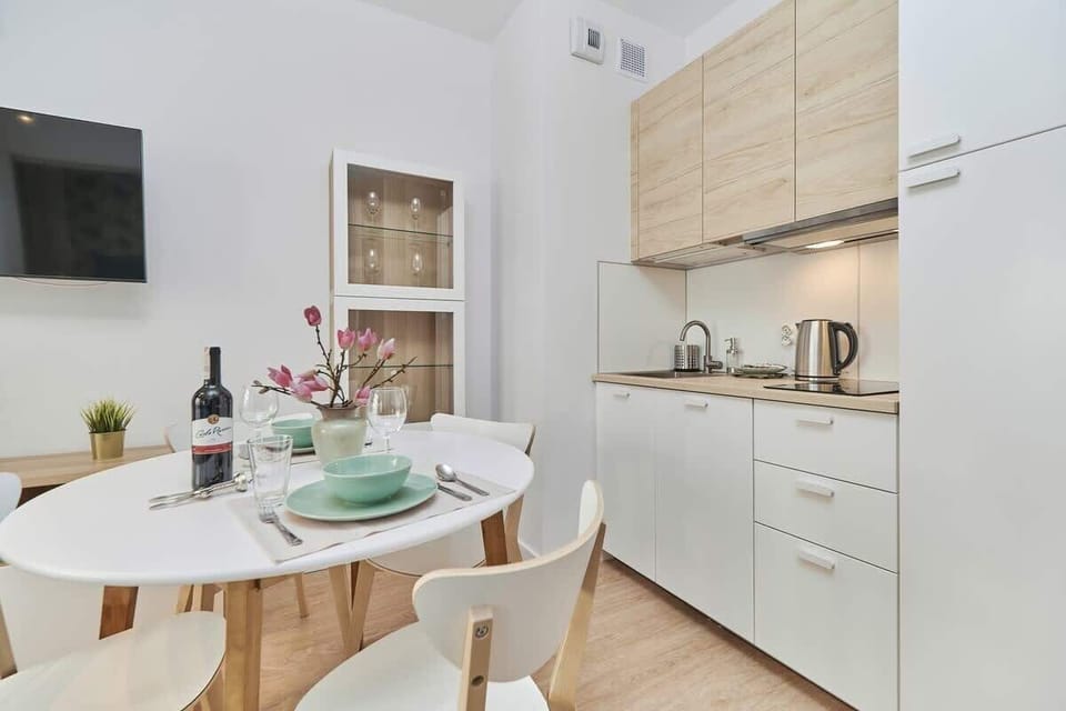 Another view of the kitchen, focusing on the counter setup with utensils, dishes, and a small dining area nearby.